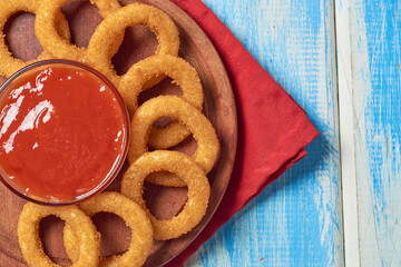 Homemade crunchy fried onion rings with tomato sauce