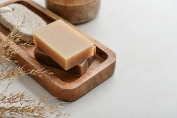 Natural soap bars and pumice stone on wooden tray