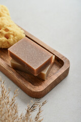 Natural soap bars and pumice stone on wooden tray