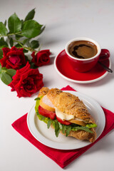 Crispy croissant with ham, cheese and vegetables with a cup of coffee