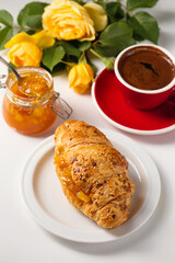 Croissant with orange jam on a late