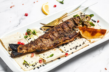 Baked trout fish with salt, lemon. Grilled trout. Fish dish fried fish fillet with vegetables on a light background. Ketogenic, keto or paleo diet lunch, Healthy food trend. Top view