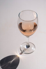 Still life scene with wine glasses on beige background in sunlight with harsh shadows. Abstract drinking wine concept.
