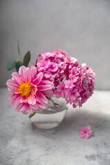 Still life pink flower bouwuet, pink hydrangea and dahlias in glass vase on neutral background soft, selective focus.
