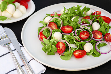 Vegetarian fresh vegetable salad with mozzarella on a white dish close-up