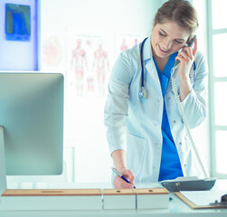 Serious doctor on the phone in her office - 524681320