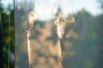 Translucent tulle separates the gazebo or window from nature. Blurry background with beige...