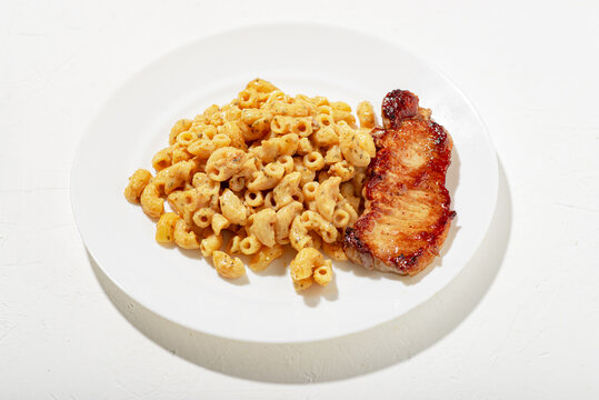Figured Italian pasta in sauce. Pieces of chopped fried meat. Minimalistic food design. White background.