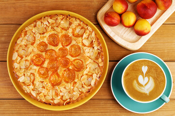 Closeup homemade pie with apricots and cup of coffee cappuccino on wooden table. Top view.