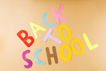 Back to school on a beige background. Inscription Back to school with hand-cut paper letters. Education concept