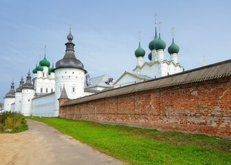 View of the wall, towers and domes of the churches of the ancient Rostov Kremlin under the blue sky. - 524683908