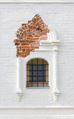 Figured arched barred window in ancient white brick wall. Medieval architecture. - 524683909