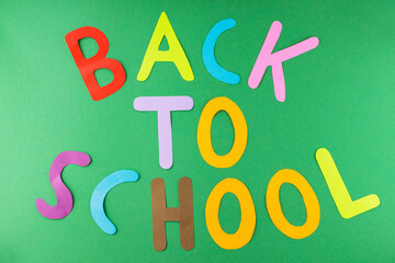 Inscription Back to school with multicolored paper letters. Back to school on a green background. School education concept