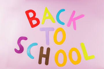 Inscription Back to school with colored letters on a pink background. Back to school concept