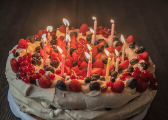 bezowy tort urodzinowy z owocami oraz świeczkami