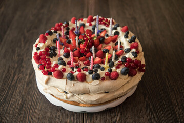 bezowy tort urodzinowy z owocami oraz świeczkami