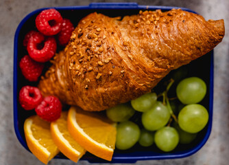 Lunch box with a sandwich croissant and fruit healthy snacks for school
