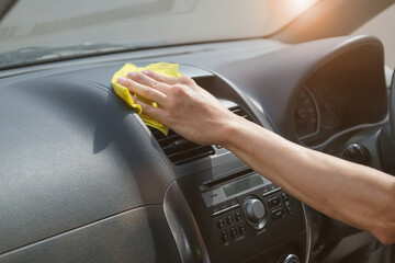 Person clean with wipe napkin the dashboard of the car in the sunlight