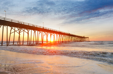 Kure Beach Fishing Pier at sun rise with colorful clouds, Kure Beach, North Carolina, USA. Kure beach is the home to the oldest fishing pier on the Atlantic Coast and an oceanfront park.