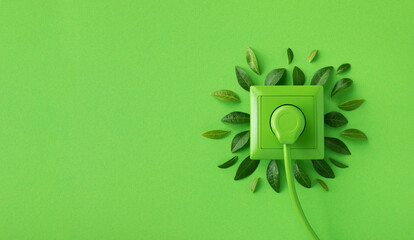Green outlet or wall socket and power cord with fresh leaves top view. Renewable and saving energy,...