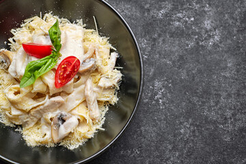 Fettuccine pasta with tomatoes on a black plate