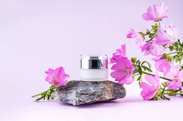 jar for cosmetics on the podium made of stone and flowers on a purple background