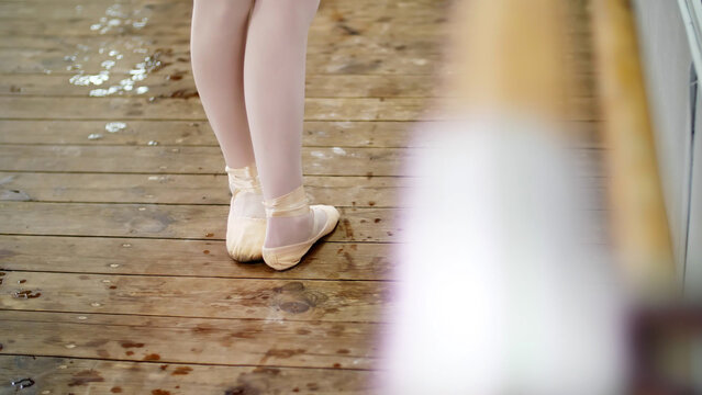 close up, in dancing hall, ballerina in ballet shoes performs tendu aside, grand battement, elegantly, standing near barre at mirror in ballet class. High quality photo