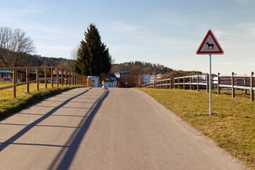 road with attention horses sign in this area is to be expected increasingly with riding horses, cloudless blue sky without people
