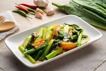Stir fried Chinese broccoli with sun-dried salted fish and oyster sauce on white plate