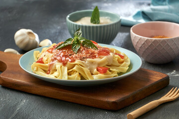 Tagliatelle Spaghetti pasta in tomato sauce on a turquoise wooden plate and black base. Italian food