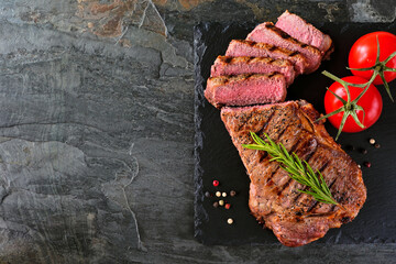 Delicious grilled steak sliced. Overhead view on a dark slate background with copy space.