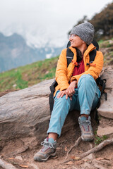 Portrait of teenager girl hiker relaxing in mountains during Bhrigu Lake trek in Manali, India. Young Indian woman with backpack travelling. Wanderlust and travel concept.