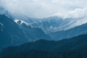 Snow covered Himalayan mountain range with clouds rolling over peaks during winter in Manali, Himachal Pradesh, India. Indian travel destination. Winter mountain landscape