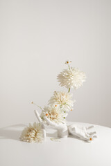 White hands on a white table hold fresh flowers. Original stylish bouquet
