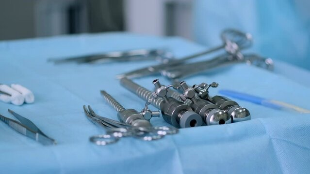 New samples of medical bipolar laparoscopic clamps (scissors) of various types and purposes in the operating room. Laparoscopic scissors and graspers on blue desk.