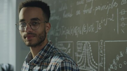 Chest up portrait shot of young biracial student posing for camera near chalkboard in college classroom - Powered by Adobe
