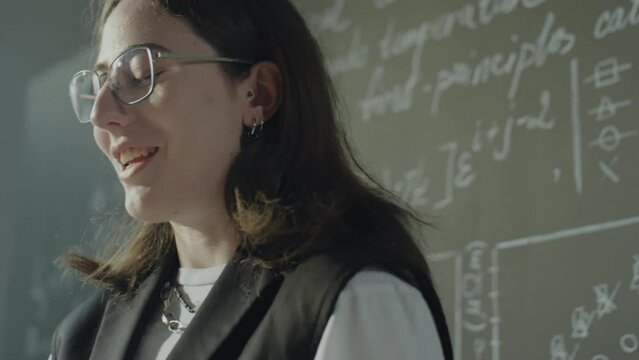 Close up shot of Caucasian female student standing with papers at lectern and talking while giving presentation during college lesson