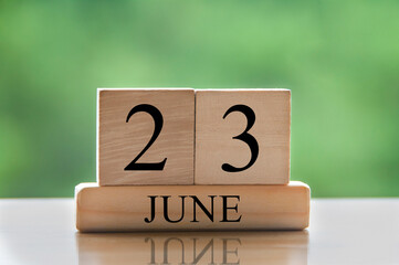 June 23 calendar date text on wooden blocks with blurred nature background. Copy space and calendar concept