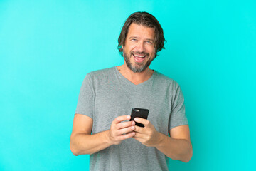 Fototapeta premium Senior dutch man isolated on blue background surprised and sending a message