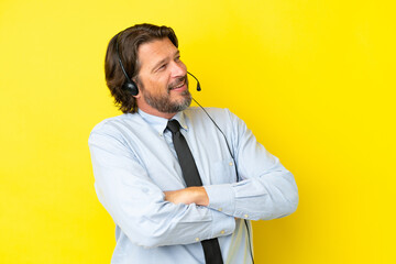 Telemarketer dutch man working with a headset isolated on yellow background happy and smiling