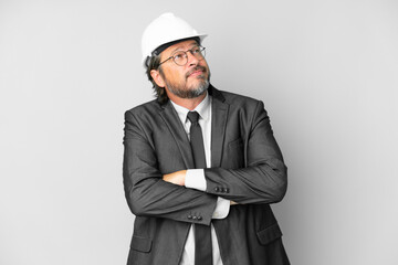 Young architect man with helmet over isolated background making doubts gesture while lifting the shoulders