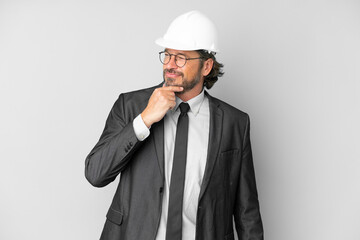 Young architect man with helmet over isolated background looking to the side