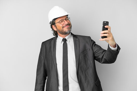 Young architect man with helmet over isolated background making a selfie