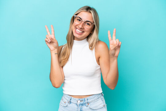 Young caucasian woman isolated on blue background showing victory sign with both hands