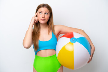 Young woman holding beach ball in holidays isolated on white background having doubts and thinking