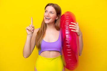 Young caucasian woman holding air mattress isolated on yellow background intending to realizes the solution while lifting a finger up