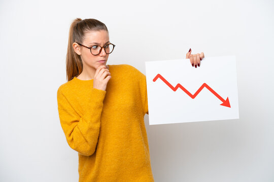 Young caucasian woman isolated on white background holding a sign with a decreasing statistics arrow symbol and thinking