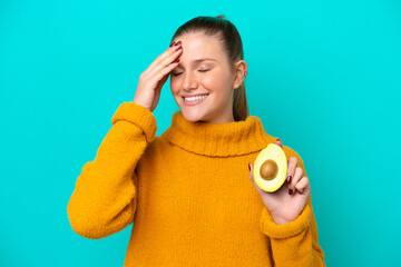 Young caucasian woman holding an avocado isolated on blue background has realized something and intending the solution