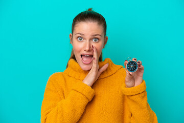 Young caucasian woman holding compass isolated on blue background whispering something