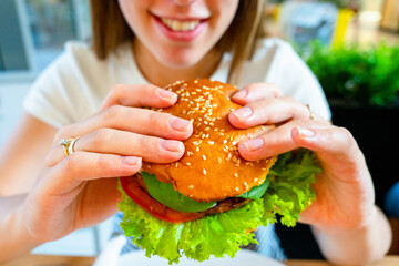 Veggie sandwich healthy vegan burger. Cute cheerful girl eating vegetarian hamburger with salad,...